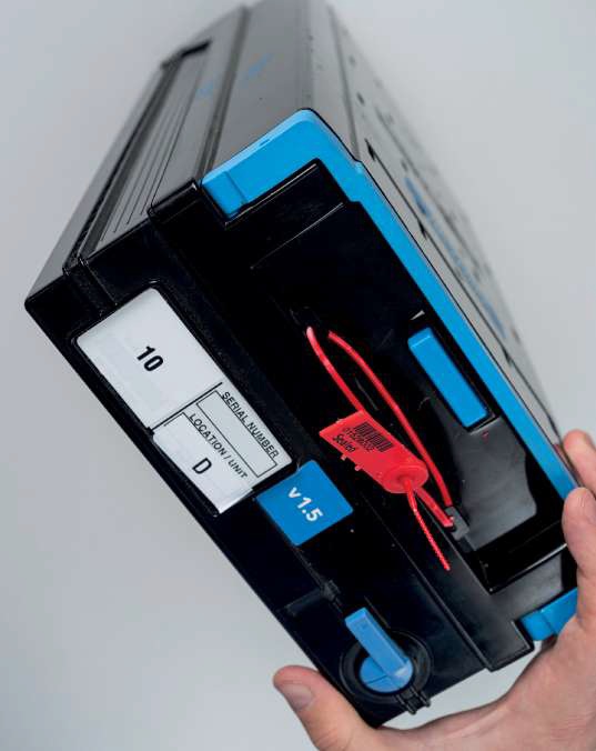 Cassete Security seals - Ойросекюрити | Eurosecurity Small Black Electronic Cartridge with Blue Accents and a Red Zip Tie Being Held by Two Hands filename Eurosecuritybg