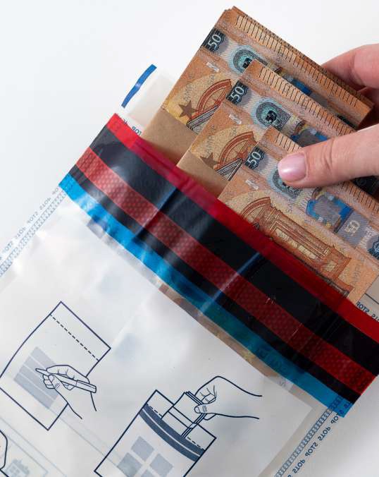 Close up of a Hand Inserting Several 50 euro Banknotes into a Striped Cash Bag filename  Eurosecuritybg
