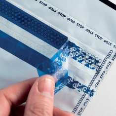 Close up of a Hand Peeling Blue Protective Film from a Clear Plastic Sheet Exposing Printed Warning Text Along the Edge filename  Eurosecuritybg